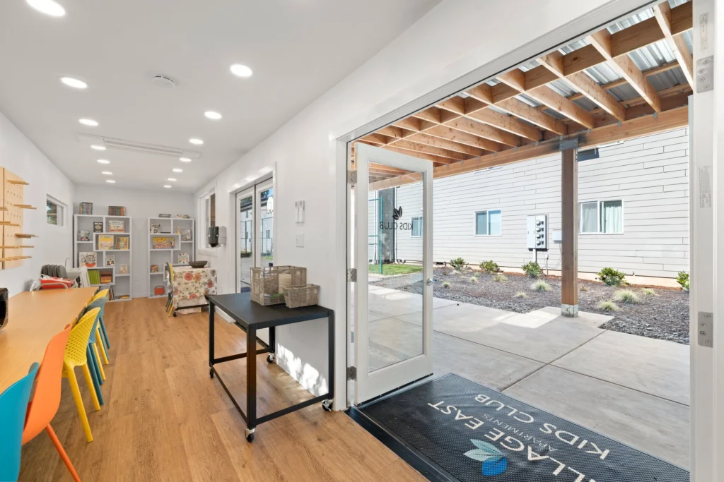 kids club room with desks and chairs and a shelf full of books and games