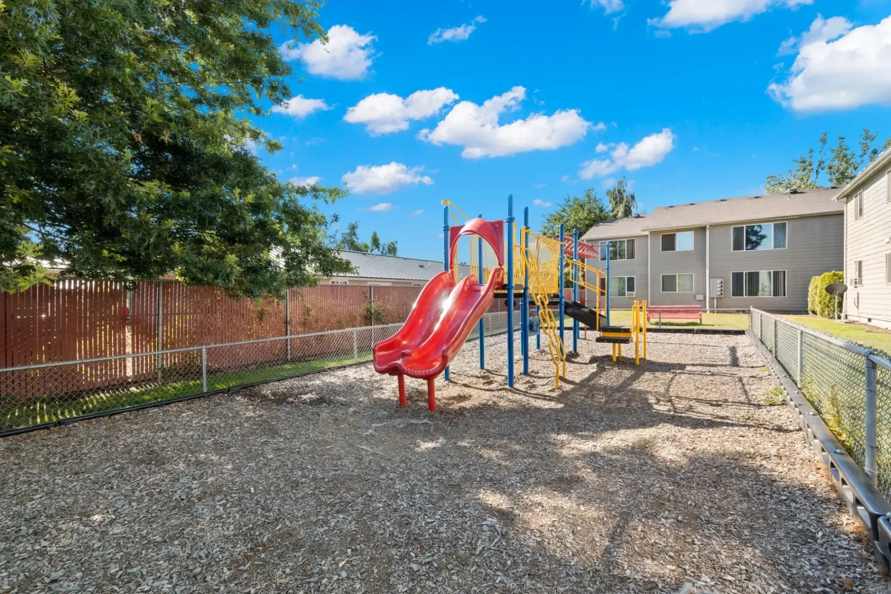 Fenced playground with climbing and slides