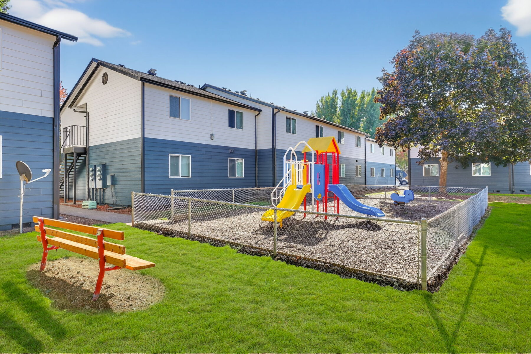 Fenced playground with climbing and slides